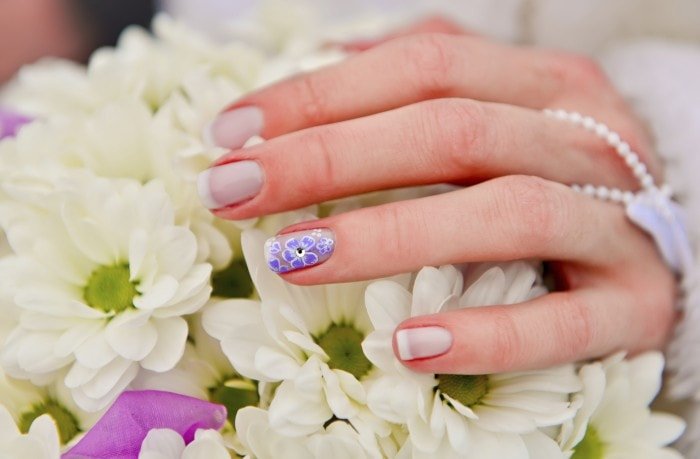 Bride hands manicure on the white bouque
